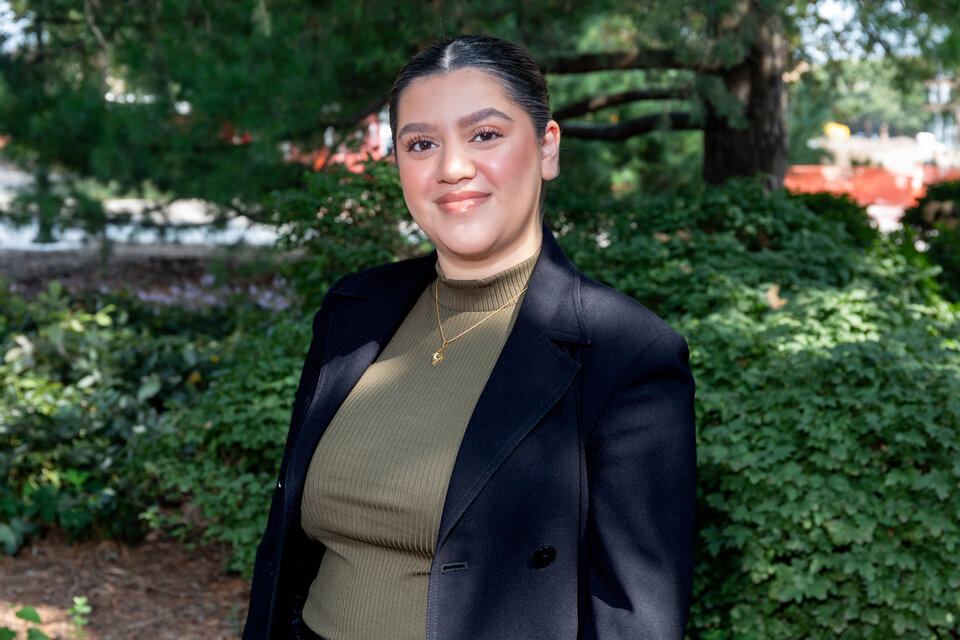 Headshot of Amber Magallon. Outdoors, wearing moss green shirt and black blazer.