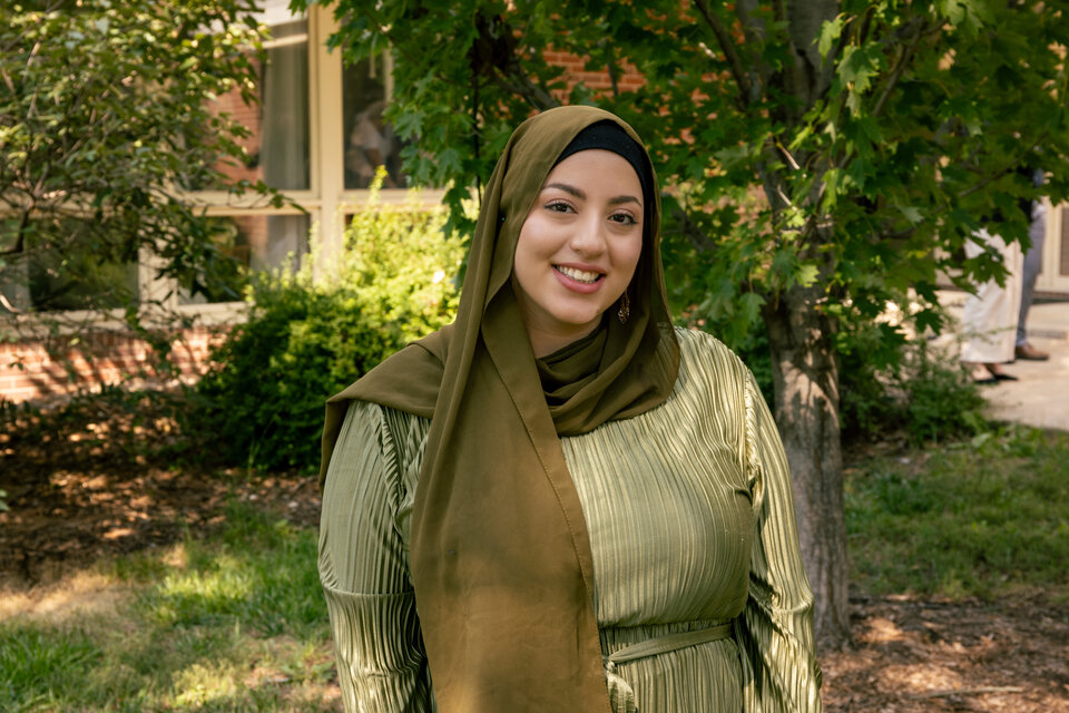 Headshot of Kadeja Alkanass. Outdoors, wearing a green dress and a green hijab..