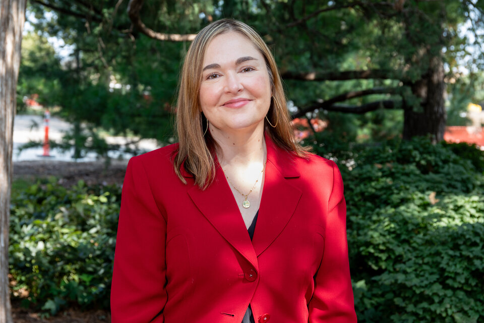 Headshot of Karen Starr. Outdoors, wearing a red blazer.