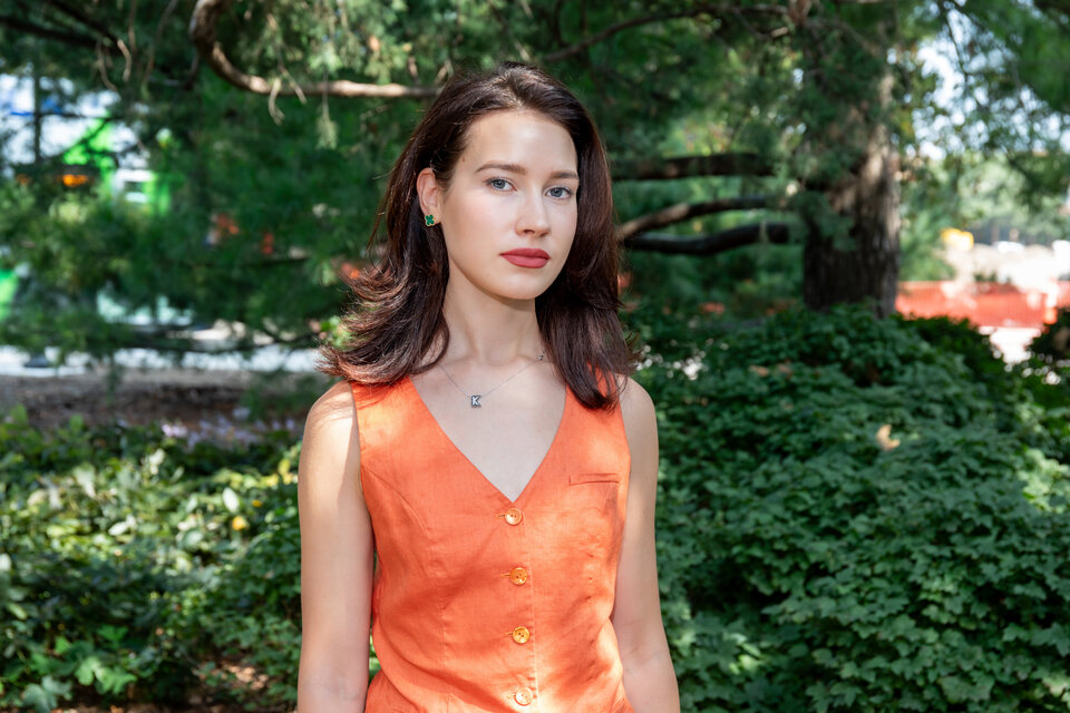 Headshot of Kateryna Potorocha. Outdoors, wearing an orange dress.