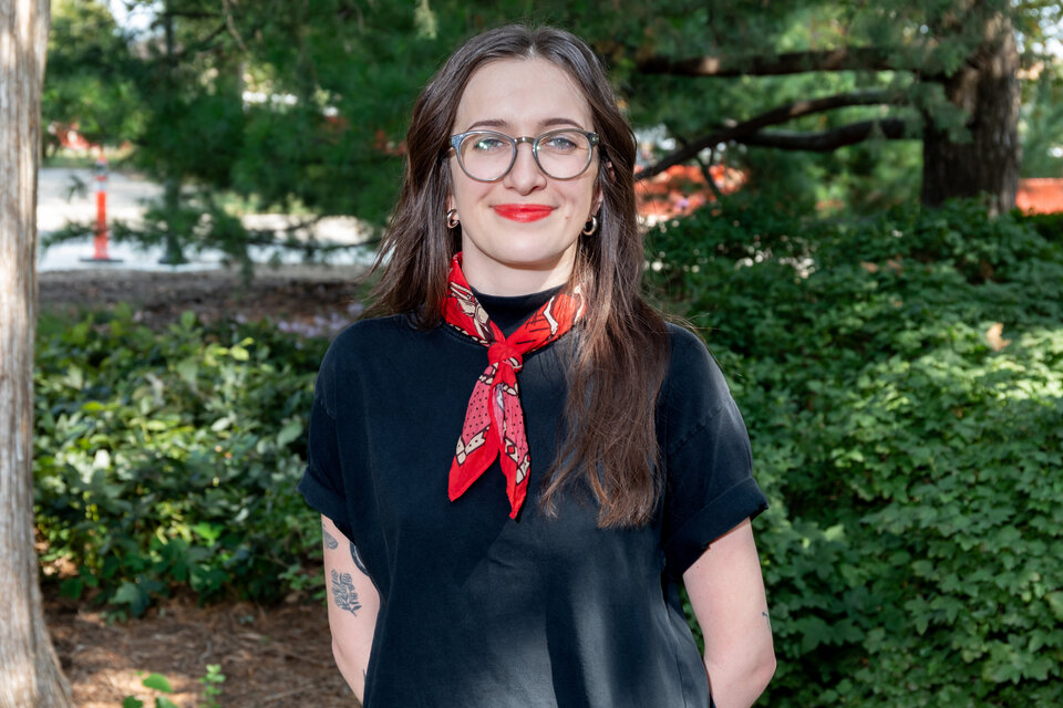 Headshot of Tadia Musgrave. Outdoors, wearing a black blouse and a red neckerchief.